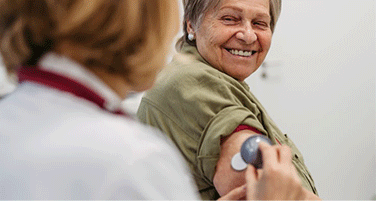 Arts die de bovenarm van een oudere vrouw onderzoekt tijdens een consult.